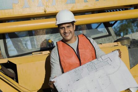man smiling holding a blueprint